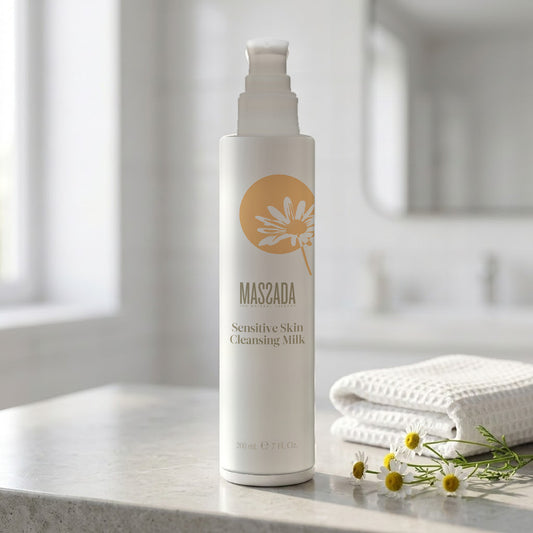 Massada Leche Limpiadora Pieles Sensibles 200 ml en un baño luminoso, junto a una toalla de nido de abeja y flores blancas