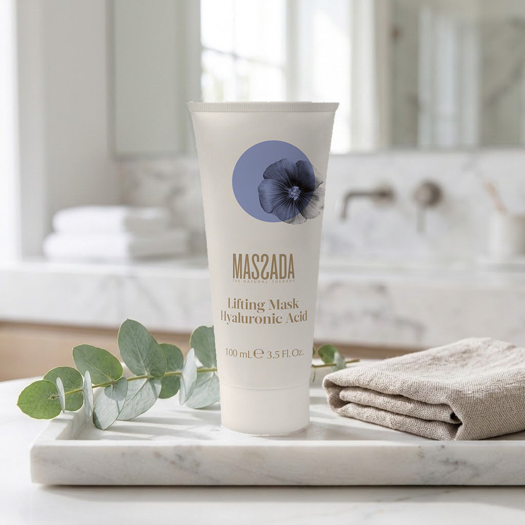 Massada Lifting Mask Hyaluronic Acid 100 ml sobre bandeja de mármol en un baño, junto a hojas verdes y una toalla