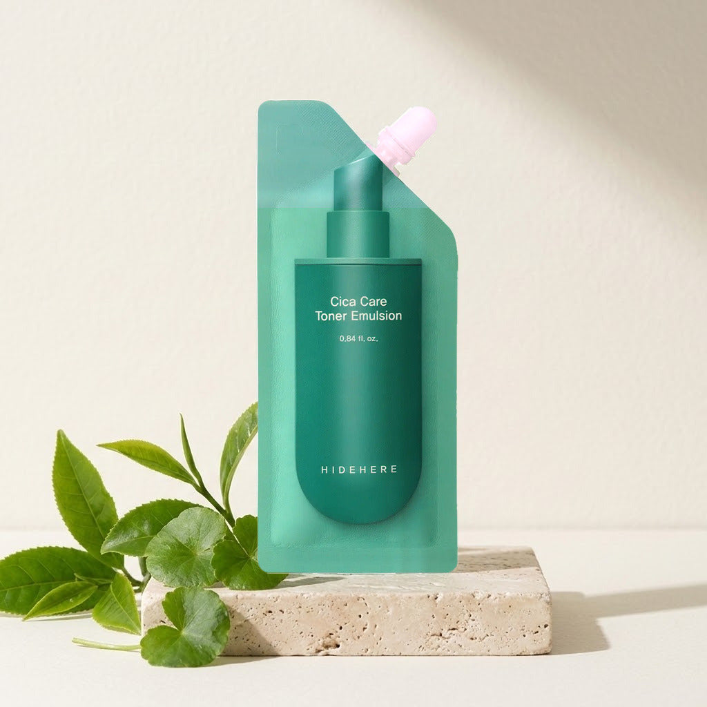 Hidehere Cica Care Toner Emulsion 25 ml sobre una bandeja de travertino, junto a unas hojas verdes