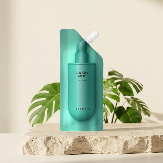 Hidehere Cica Care Cream 25 ml sobre una losa de piedra clara con plantas de hojas verdes detrás