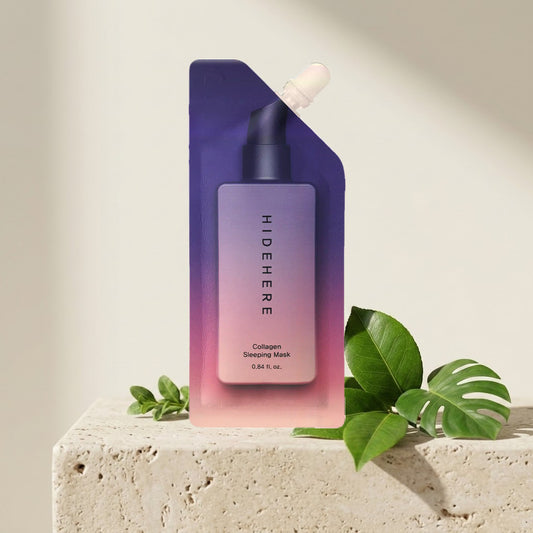 Hidehere Collagen Sleeping Mask 25 ml sobre un bloque de travertino, junto a una hoja de monstera y ramas verdes