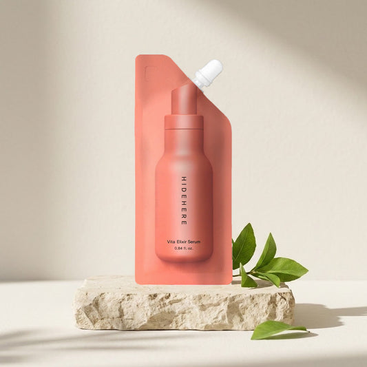 Hidehere Vita Elixir Serum 25 ml sobre una piedra clara junto a una rama de hojas verdes