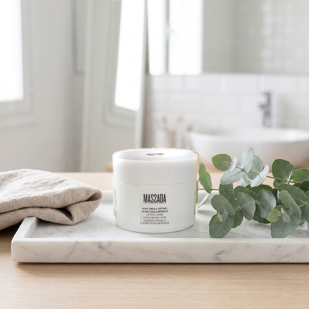 Massada Mascarilla Lifting Ácido Hialurónico 200 ml en bandeja de mármol del baño con hojas verdes y toalla beige