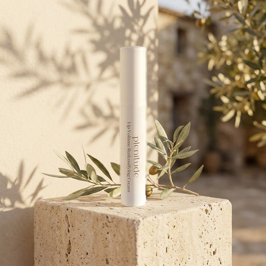 Massada Plenitude Lip Volume 15 ml sobre un bloque de piedra al sol, junto a una rama de hojas verdes