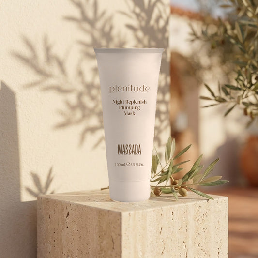 Massada Plenitude Plumping Mask 100 ml sobre un bloque de piedra clara junto a una rama con hojas verdes