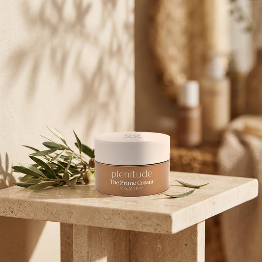 Massada Plenitude The Prime Cream 50 ml sobre una mesa de piedra clara junto a una rama de hojas verdes