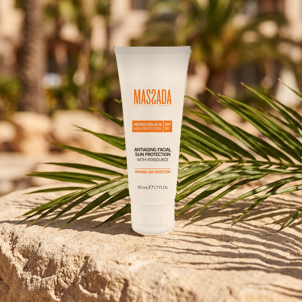 Massada Protección Solar Antiedad SPF 50 (Con Color) 50 ml sobre una roca al sol con hojas verdes detrás