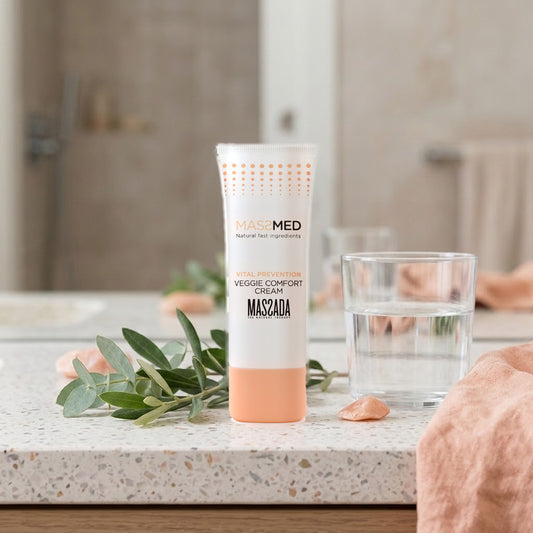 Massada Veggie Comfort Cream 30 ml sobre encimera de terrazo en el baño, con hojas verdes y un vaso de agua